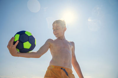 Low angle view of shirtless boy against sky