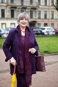 Portrait of woman standing against wall in city