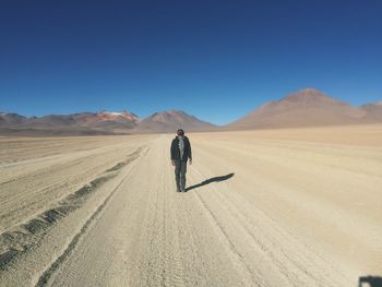 Man on sand dune in desert against clear sky