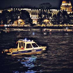 Boat in river against illuminated buildings at night