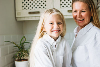 Happy blonde long hair mom and daughter in the kitchen, healthy lifestyle