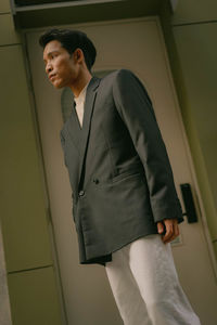 Portrait of young man standing against wall