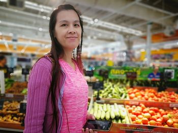 Portrait of smiling woman standing at supermarket