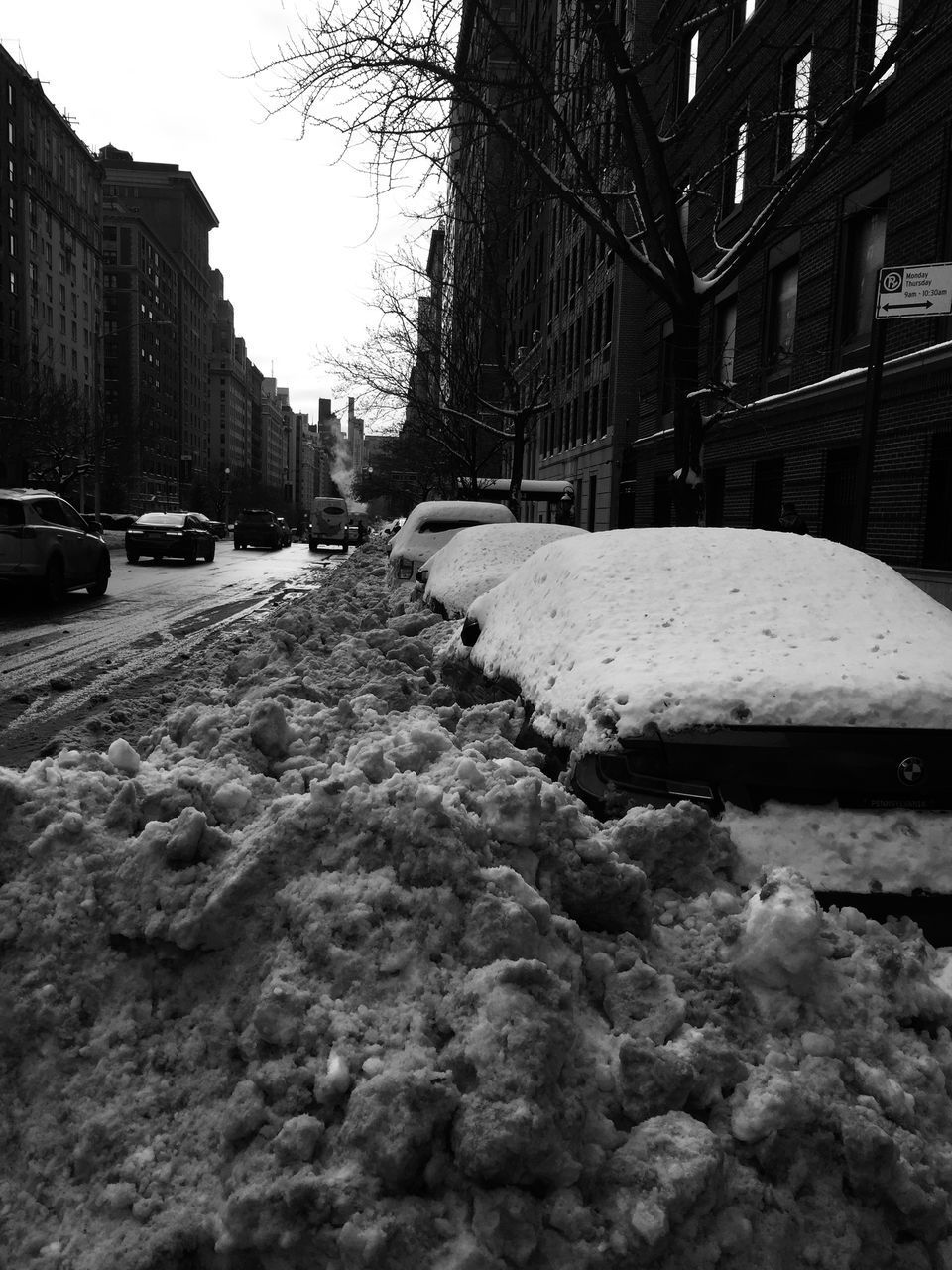 SNOW COVERED ROAD BY BUILDINGS AGAINST SKY