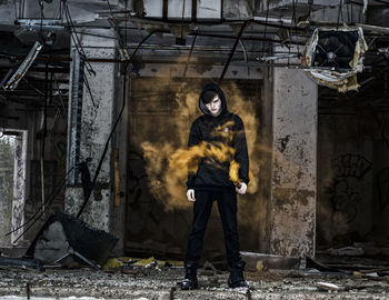 Full length of man holding distress flare in abandoned building