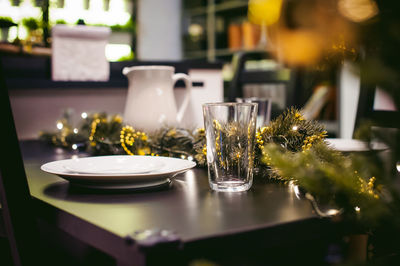 Close-up of plate and drinking glass with christmas decorations on table