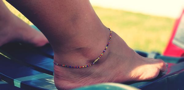 Low section of woman wearing bracelet at beach