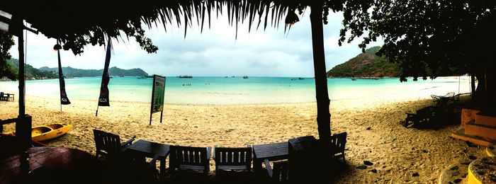 Chairs and tables on beach against sky