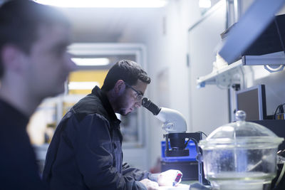 Man using a microscope in a sensor technology plant