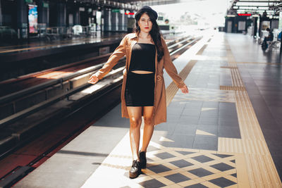 Portrait of young woman standing on railroad station platform