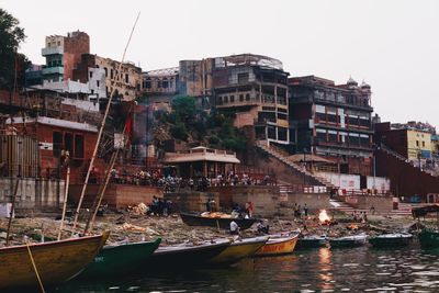 Boats moored in canal amidst buildings in city against sky