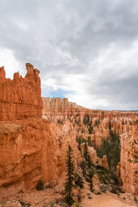 Rock formations on landscape against cloudy sky