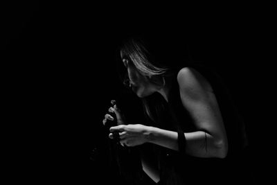 Mid section of woman holding necklace over black background