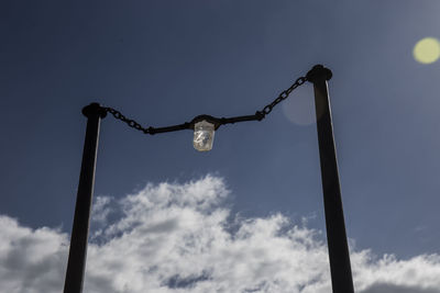 Low angle view of silhouette poles against blue sky