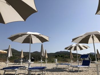 Lounge chairs and umbrellas on beach against sky