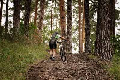 Rear view of man with bicycle in forest