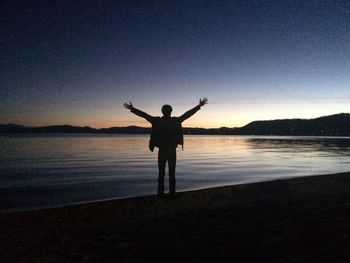 Silhouette of woman standing on beach at sunset