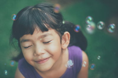 Close-up of smiling girl with bubbles at public park