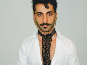 Portrait of young man standing against white background