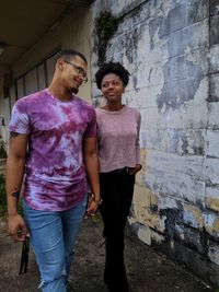 Portrait of young couple standing against wall