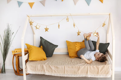 Low section of woman sitting on bed at home