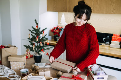 Side view of young woman sitting on table at home
