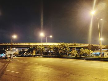 Illuminated street against sky at night