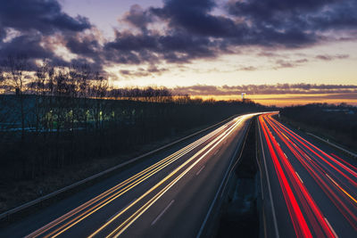 Light trails on road against sky at sunset