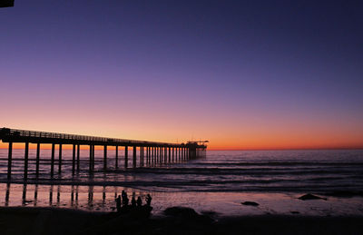 Pier over sea against sky at sunset