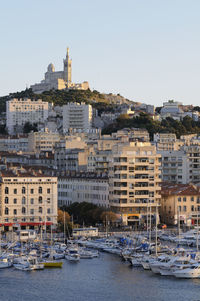 Sailboats moored on river by buildings against clear sky