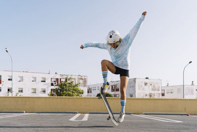 Young woman with skateboard skating on rooftop at city