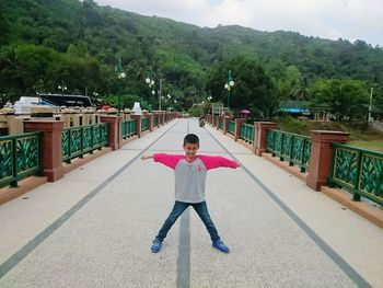 Full length of young woman standing against trees