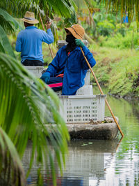 Rear view of people sitting by lake