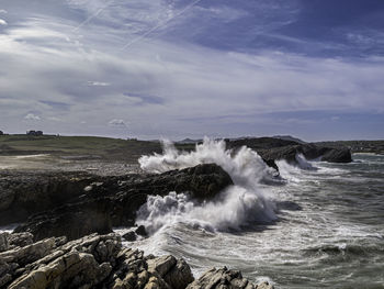 Waves splashing on sea against sky