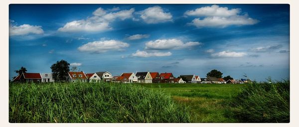 Houses on field against cloudy sky