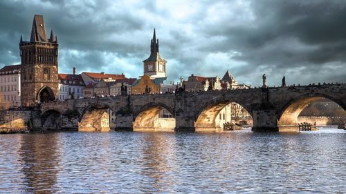 Arch bridge over river against buildings in city