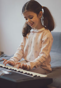 A little girl plays the electric piano.