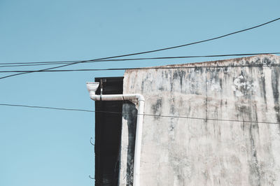 Low angle view of telephone pole against clear blue sky