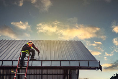 Low angle view of man on built structure against sky