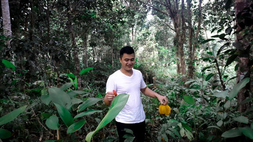 Portrait of young man standing against plants