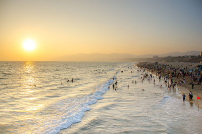 People on beach against sky during sunset