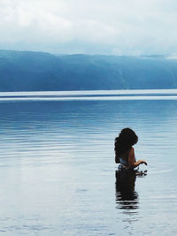 Rear view of man swimming in sea against sky