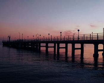 Silhouette pier over sea against sky during sunset