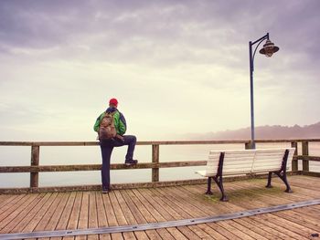 Thinking man on wooden pier on the background of sea hidden in mist. wooden sea bridge early autumn 