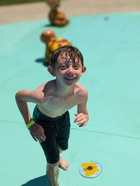 Portrait of boy playing with arms outstretched standing on swimming pool