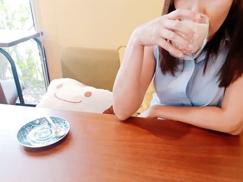 Midsection of woman sitting on table at home