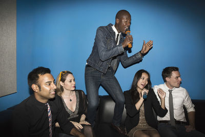 Cheerful friends singing karaoke in nightclub