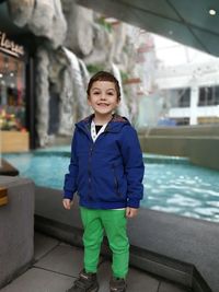 Portrait of smiling boy standing against fountain