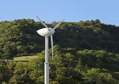 Traditional windmill in forest against clear sky
