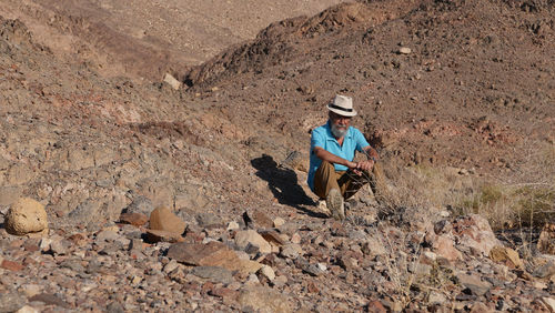 Senior man sitting on rock in the desert 